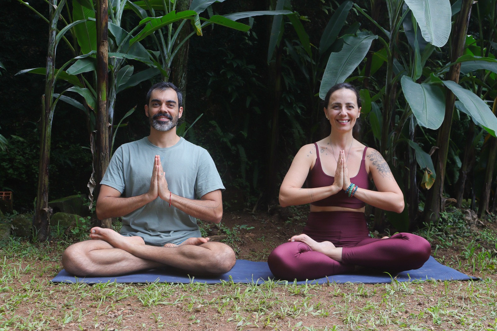 Leandro Brito e Ju Sónvez em postura de meditação na natureza